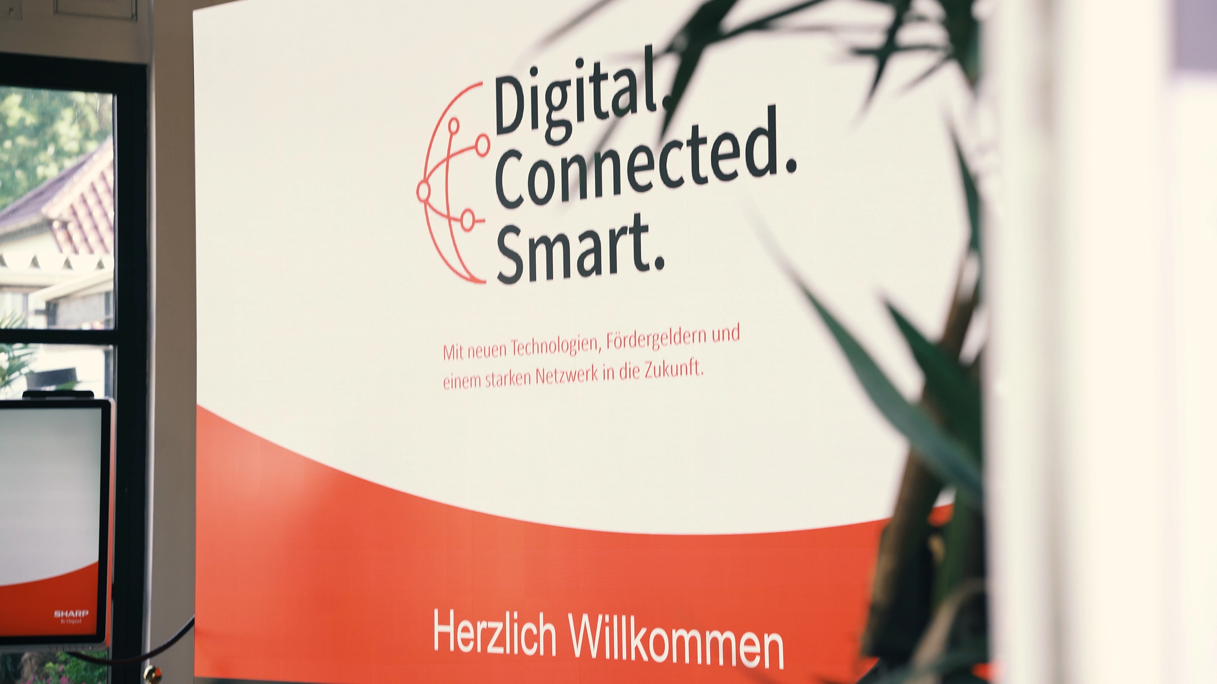 "Herzlich Willkommen" Schild mit der Aufschrift "Digital Connected Smart" und Informationen zu neuen Technologien und Netzwerken.