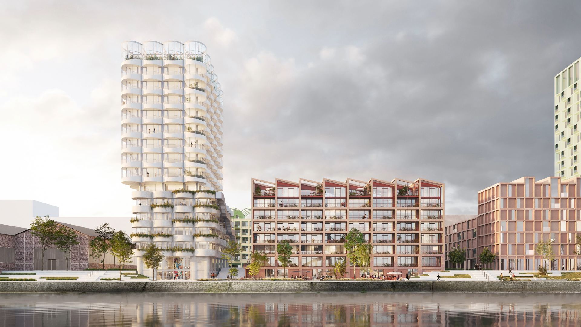 Moderne Stadtarchitektur am Wasser. In der Bildmitte befindet sich ein auffälliges, hohes Gebäude mit einer besonderen, runden Architektur. Das Hochhaus hat viele leicht geschwungene Balkone und Terrassen, die sich in einem regelmäßigen Muster um das Gebäude winden. Diese Balkone wirken wie übereinander gestapelte Ringe oder Wellen und geben dem Haus eine sehr organische und moderne Ausstrahlung. Die Fassade ist überwiegend hell gehalten und wirkt freundlich, fast transparent durch die vielen Glasflächen. Links und rechts davon sieht man mehrere weitere Gebäude. Sie sind niedriger als der Turm in der Mitte und haben eher eine quaderförmige, kantige Bauweise. Viele dieser Gebäude bestehen aus mehreren Etagen, mit großen Fenstern und Balkonen. Die Fassaden der meisten dieser Häuser sind in Rottönen gehalten - sie erinnern ein wenig an Backstein, haben aber trotzdem einen modernen Look. Einige Balkone sind mit Pflanzen bestückt. Im Vordergrund ist eine Wasserfläche, die wie ein Kanal oder Hafenbecken aussieht. Die Gebäude spiegeln sich im ruhigen Wasser. Die ganze Szene wirkt wie ein neues, modernes Stadtquartier am Wasser. mit viel Wert auf lichtdurchflutete Räume, interessante Balkone und einer lebendigen Mischung aus verschiedenen Gebäudehöhen und -formen. Es wirkt harmonisch und urban, aber freundlich gestaltet.